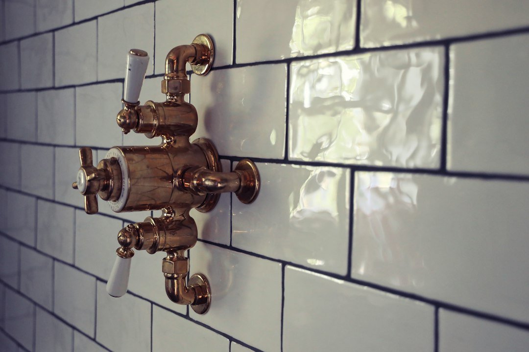 Brass shower valve set into a tiled shower wall, a penetration that must be sealed into the waterproofing