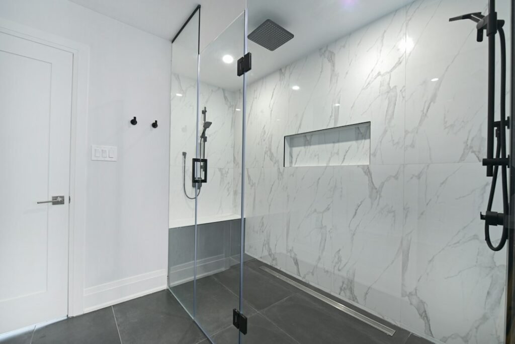 Modern tiled walk-in shower with a frameless glass panel and low-threshold entry