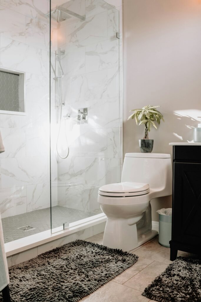 Bathroom with a glass shower enclosure, marble tile walls, and a white toilet